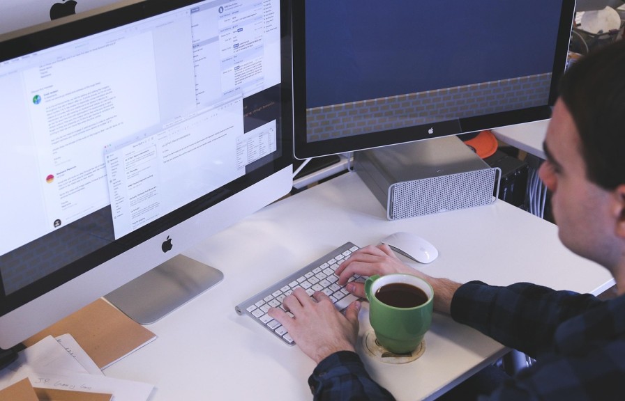 Accountant working at a desk with dual monitors, representing AML supervision and compliance planning for small firms
