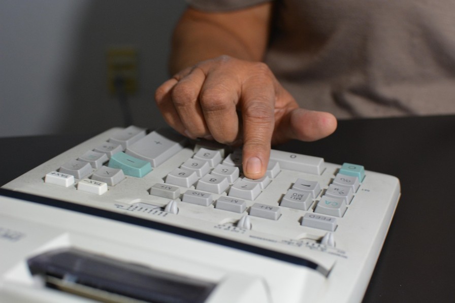 Close-up of a person using a calculator, illustrating AML supervision fees and FCA compliance costs for accountancy firms.