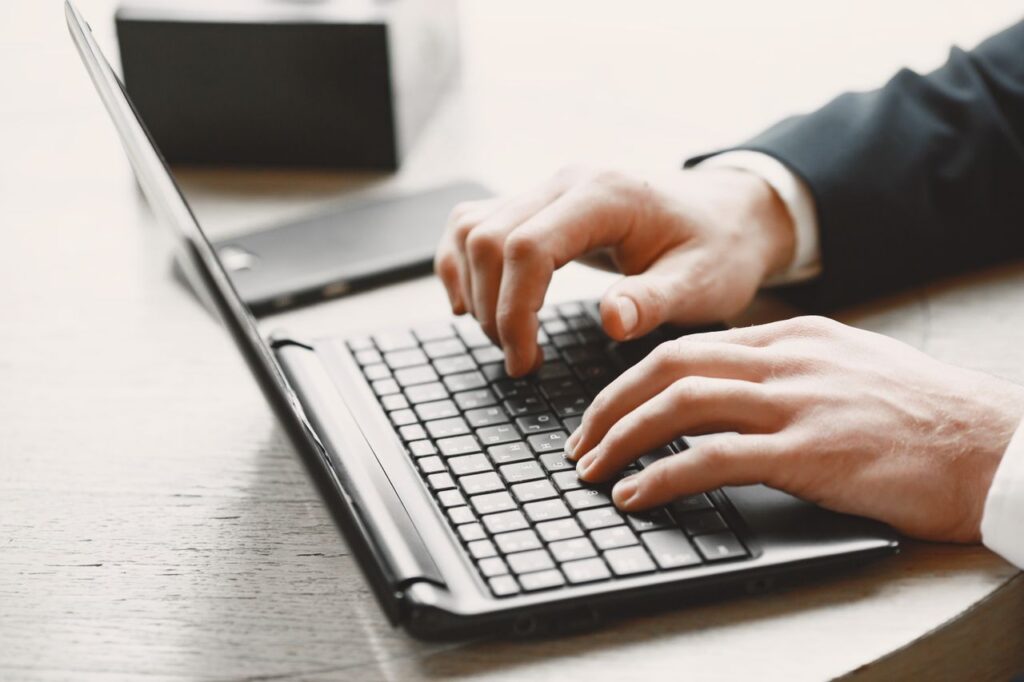 Accountant using a laptop to review remote client information for AML risk assessment.